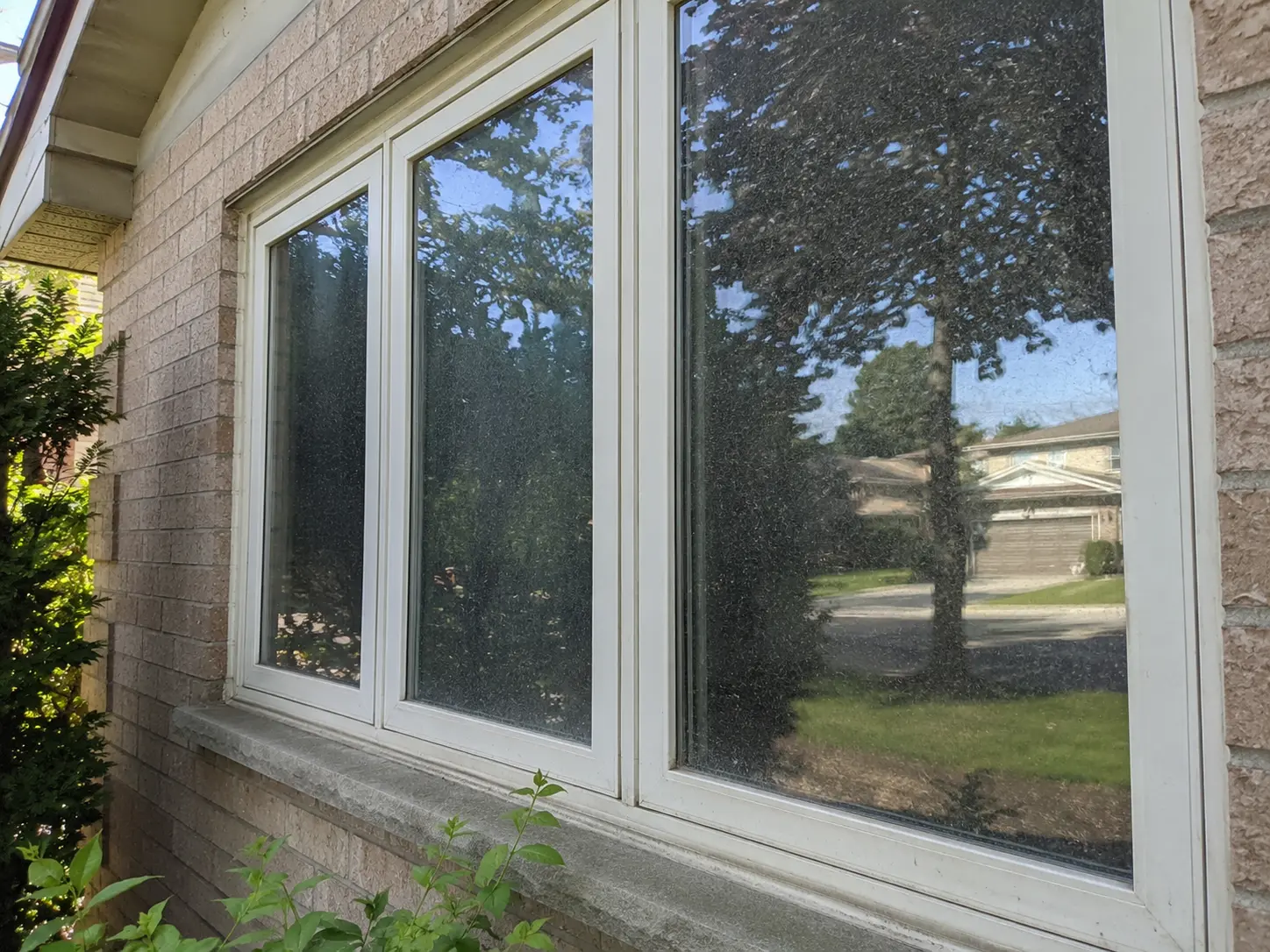 Exterior residential window with heavy water spotting before cleaning