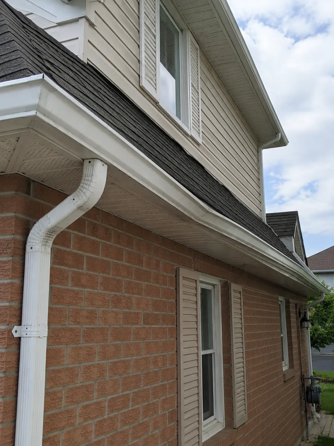 Sagging eavestrough run along the side of a brick house before repair